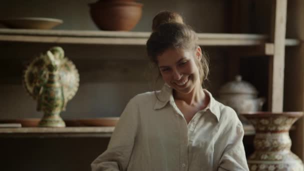 Lächelnde Frau posiert in der Werkstatt. Nahaufnahme glücklicher Künstler beim Töpfern. — Stockvideo