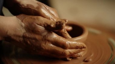 Kadın atölyede kil ürünü yontuyor. Stüdyoda kadın mankenlik yapıyor.