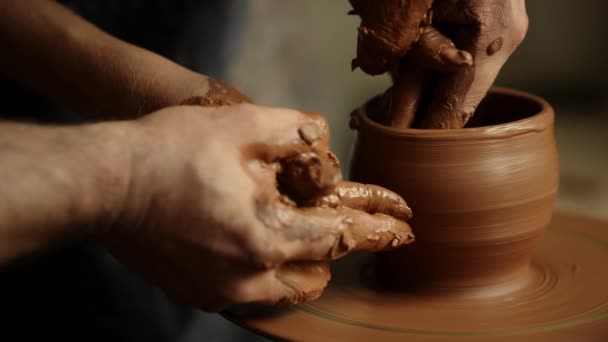 Ręce mężczyzny i kobiety robiące gliniany garnek w ceramice. Ludzie pracujący z mokrą gliną — Wideo stockowe