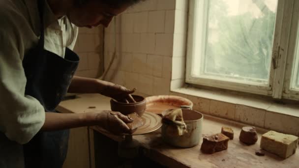 Maestro enfocado haciendo nuevo producto de arcilla en cerámica. Mujer raspando línea en la olla — Vídeos de Stock