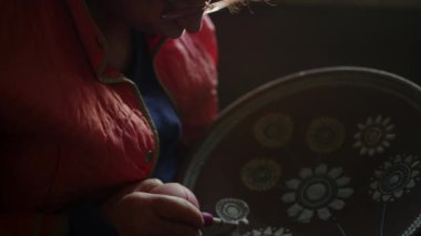 Çömlekçilikle kil ürünü dekore eden odaklanmış bir kadın. Kadın ressam tabağı