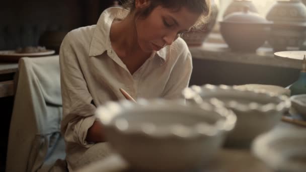 Mulher séria raspando placa de barro em cerâmica. Menina escultura no produto em estúdio — Vídeo de Stock