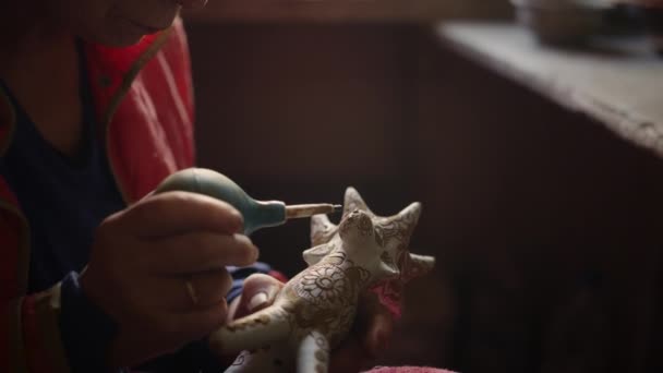나이가 많은 여자는 도기에 점을 찍는다. 장난감 말코손바닥사슴을 장식하는 여주인 — 비디오