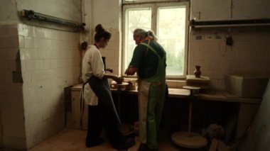 Çömlekten kil çömlek yapan genç bir kadın. Stüdyoda ana sınıfı gösteren öğretmen.