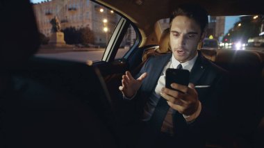 Uzaktan kumandalı işyerindeki bir adam telefonla mesaj kaydediyor. Arabadaki iş adamı