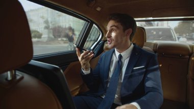 Mutlu iş adamı iş arabasındaki cep telefonuna sesli mesajla neşe paylaşıyor.