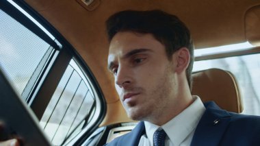 Oyuncu işadamı iş arabasında tablet bilgisayarla eğleniyor.