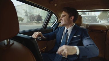 Modern arabada cep telefonuyla eğlenen yakışıklı bir iş adamı. Arabadaki adam.