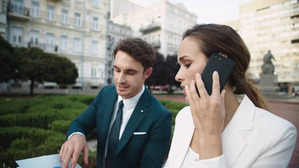 Handsome business man showing data in documents to beautiful woman in street.