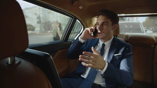 Focused business man talking on phone in interior of automobile. Man in car