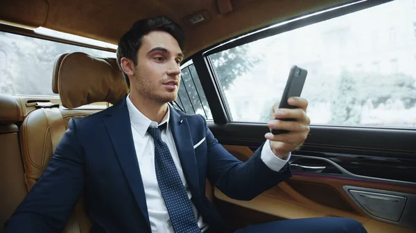 Excited business man having success at online meeting in business car.