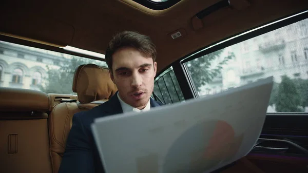 Portrait of focused business man reading documents on back seat of automobile. — Stock Photo, Image