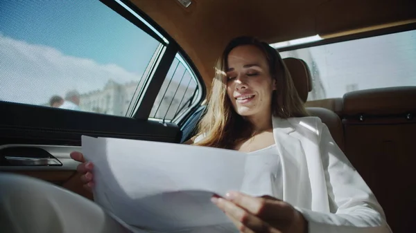 Cheerful business woman analysing statistics in documents in automobile. — Stock Photo, Image