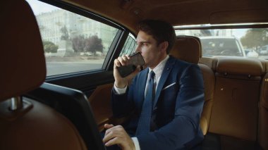 İş arabasının içinde cep telefonuyla dans eden neşeli iş adamı..