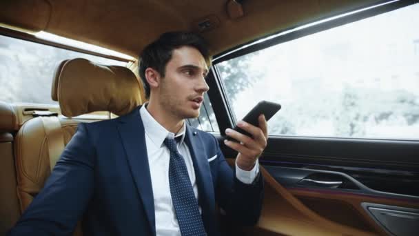 Skupiony mężczyzna profesjonalne nagranie wiadomości głosowej do smartfona w nowoczesnym samochodzie. — Wideo stockowe