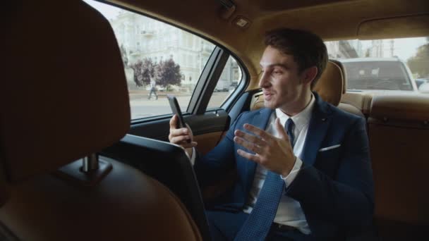 Vreugdevolle zakenman vertelt goed nieuws in videoboodschap op telefoon in zakelijke auto. — Stockvideo