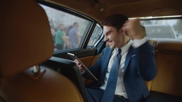 Щасливий чоловік професійного читання чудових новин на планшетному комп'ютері в сучасному автомобілі . — стокове відео