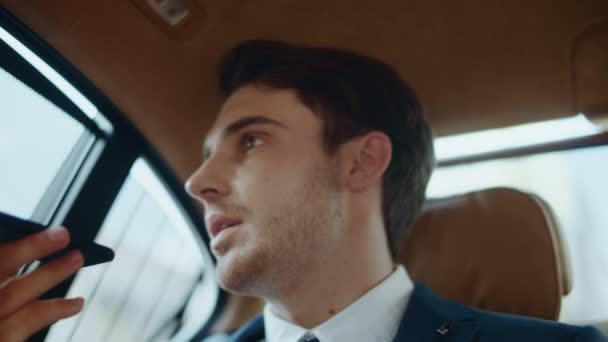 Skupiony mężczyzna profesjonalny nagrywanie wiadomości głosowej na smartfonie w nowoczesnym samochodzie. — Wideo stockowe