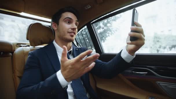 Веселий бізнесмен має відеодзвінок на мобільний телефон у бізнес-автомобілі . — стокове відео