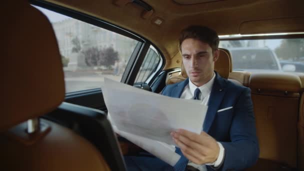 Elegante zakenman die de statistieken van papierwerk in moderne auto 's bekijkt. — Stockvideo