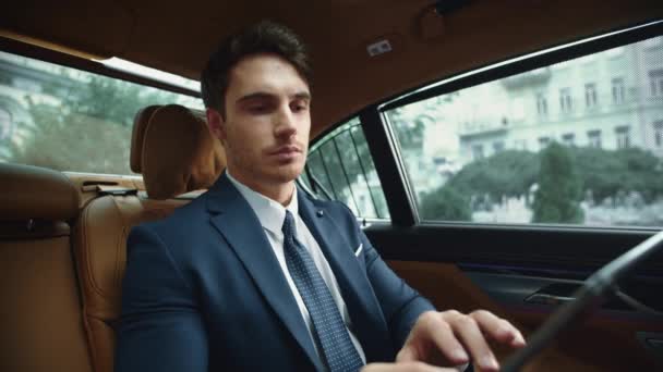 Homme d'affaires sérieux travaillant sur tablette numérique en voiture. Comprimé de lecture ceo masculin — Video