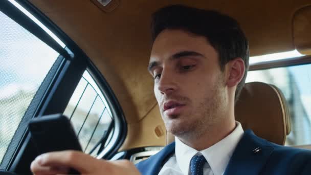 Portrait of young business man writing message on cellphone in modern car. — Stock Video
