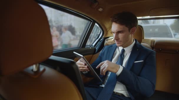 Genervter Geschäftsmann sieht schlechte Nachrichten auf Tablet-Computer im Luxus-Geschäftsauto. — Stockvideo