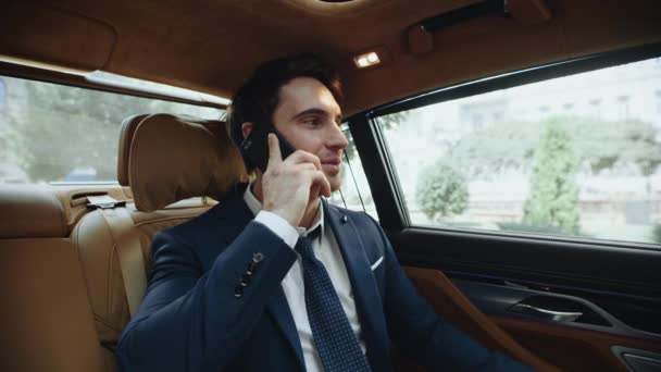 Портрет улыбающегося бизнесмена, звонящего по телефону в салоне современного автомобиля. — стоковое видео
