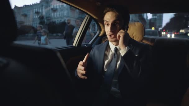 Glücklicher Geschäftsmann teilt gute Nachrichten im dunklen Geschäftsauto auf dem Smartphone mit. — Stockvideo