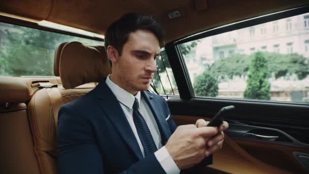 Genervter Geschäftsmann tippt Nachricht in Handy-Auto. Männlicher Ceo arbeitet im Auto. — Stockvideo