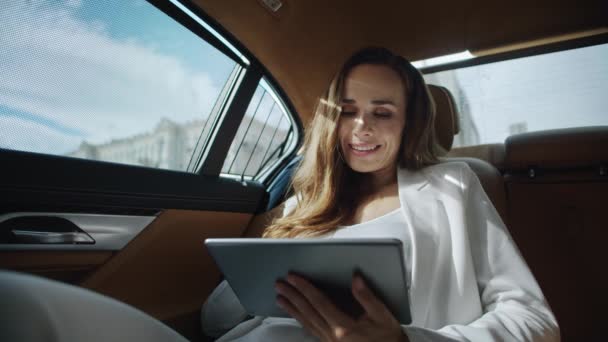 Portrait d'une femme d'affaires souriante travaillant avec une tablette numérique dans une voiture de fonction. — Video