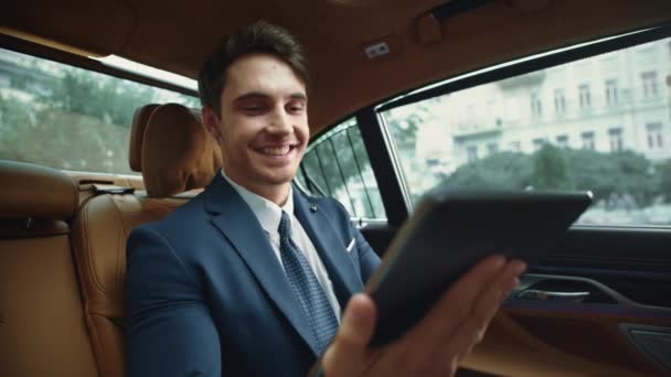 Feliz macho profesional mensajes de lectura en la tableta del ordenador en el coche de negocios. — Vídeos de Stock