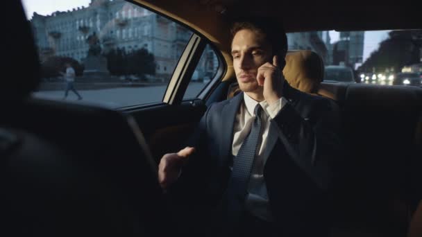 Серйозний бізнесмен розмовляє мобільним телефоном в машині. Чоловік працює в темному автомобілі — стокове відео
