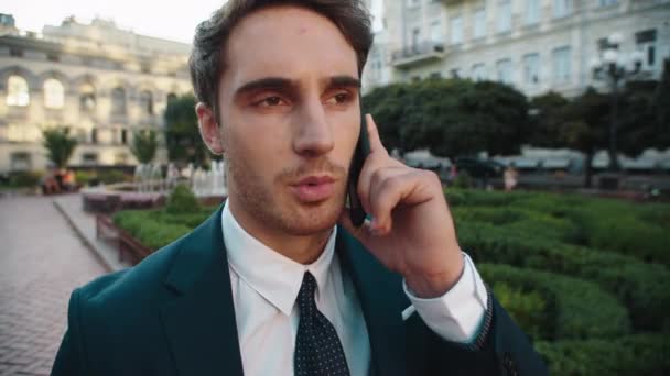Uomo d'affari serio discutere casi di lavoro sul telefono cellulare in città a piedi. — Video Stock