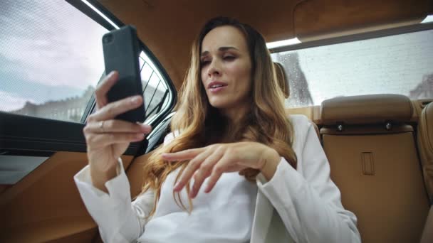 Розслаблена бізнес-леді говорить на відеодзвінок на смартфон в сучасному автомобілі . — стокове відео