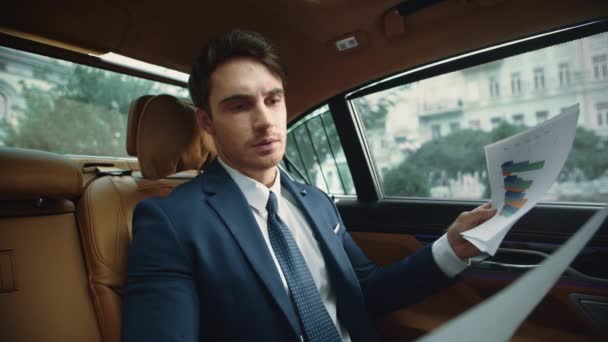 Portrait de documents de lecture professionnelle masculine ciblée dans le salon de la voiture de luxe. — Video
