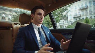 İş adamı laptopta arabada görüntülü konuşma yapıyor. Video mesajı kaydeden adam