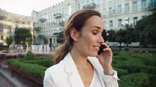 Портрет веселой деловой женщины, разговаривающей по мобильному телефону в городской прогулке. — стоковое видео