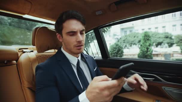 Portrait of upset business man getting bad news with smartphone in business car. — Stock Video