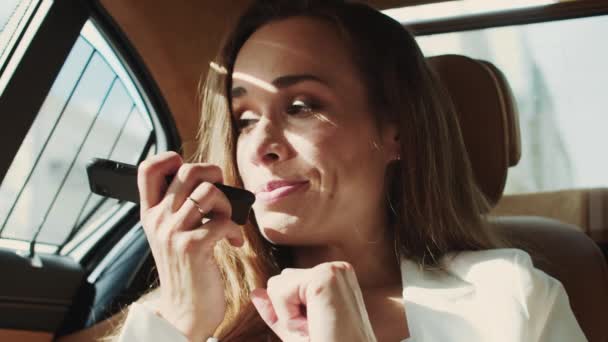 Porträtt av glad business lady inspelning röstmeddelande på smartphone i bilen. — Stockvideo