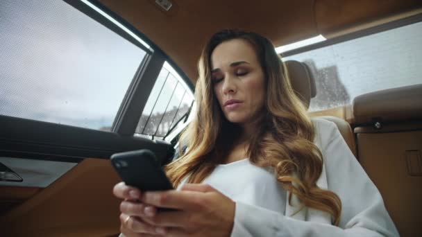 Thoughtful business woman writing message on mobile phone in luxury automobile. — Stock Video