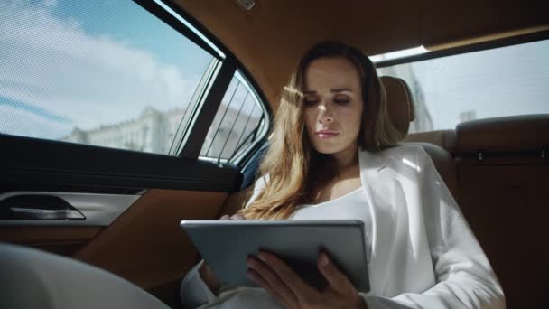 Focused business woman reading data on tablet computer in luxury car. — Stock Video