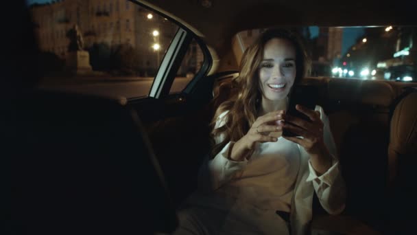 ผู้หญิงธุรกิจที่สนุกสนานหัวเราะในวิดีโอโทรบนสมาร์ทโฟนในรถธุรกิจ . — วีดีโอสต็อก