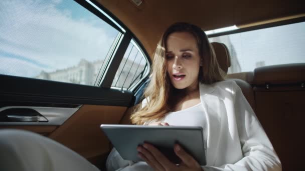Έκπληκτος επιχειρηματίας που διαβάζει καλά νέα στον υπολογιστή tablet σε πολυτελές αυτοκίνητο. — Αρχείο Βίντεο