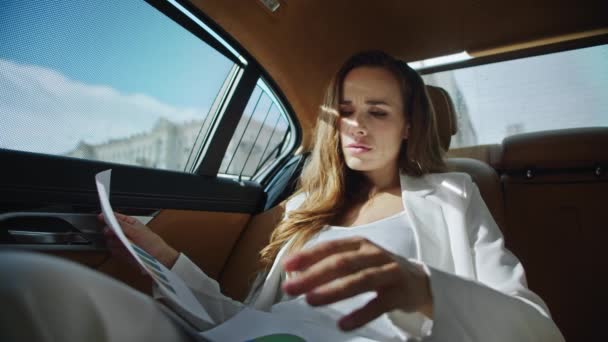 Gericht zakenvrouw op zoek naar gegevens in documenten in comfortabele moderne auto. — Stockvideo