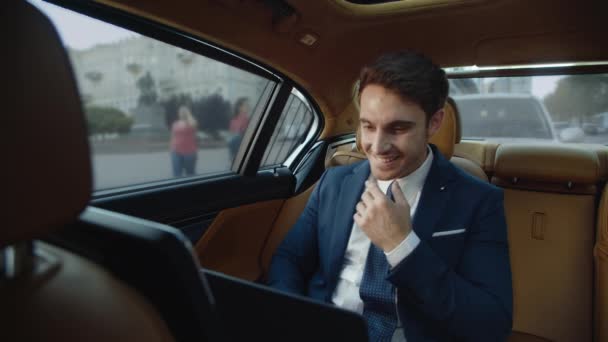 Homem de negócios sorridente conversando no computador portátil em automóvel de luxo. — Vídeo de Stock