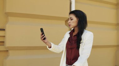 Dışarıda video görüşmesi yapan üzgün ırklı kadın. İş kadını dışarıda yürüyor..