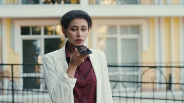 Ciddi melez kadınlar dışarıda akıllı telefondan projeyi tartışıyorlar. Konuşan telefon