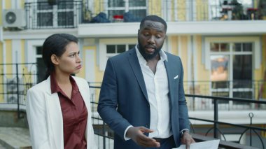 Dışarıda yürüyen melez bir çift. İş adamları açık havada projeyi tartışıyor.