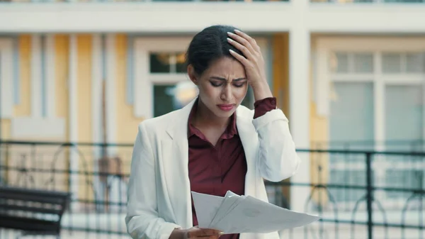 Sad businesswoman feeling upset with project data outdoors, Lady reading papers